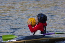 Kind mit Ball im Kanu-Polo Boot